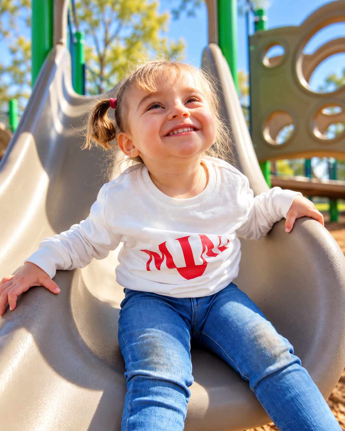 Harper smiling on a playground slide in the sunshine